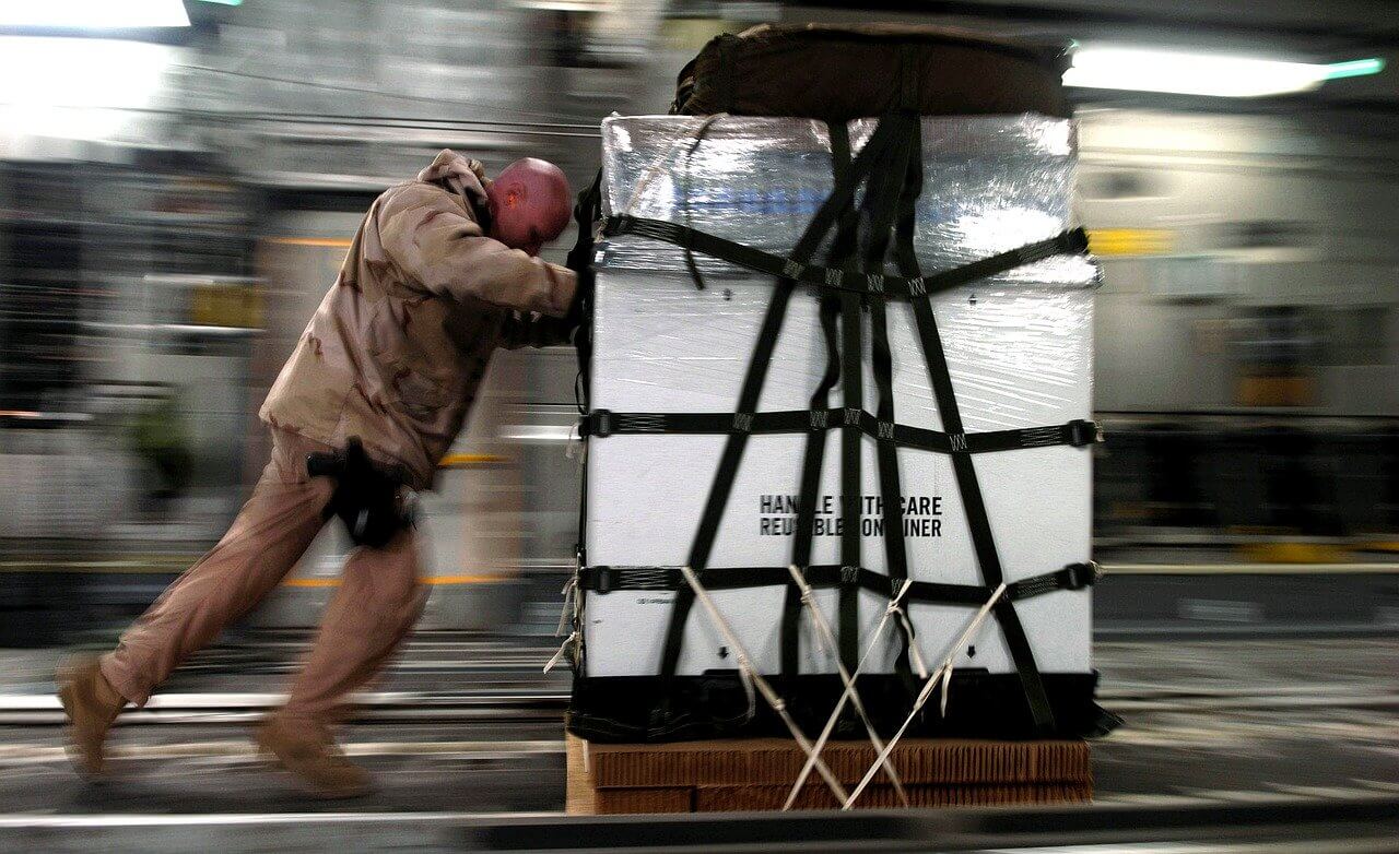 man dressed in camo pushing skid loaded with cargo